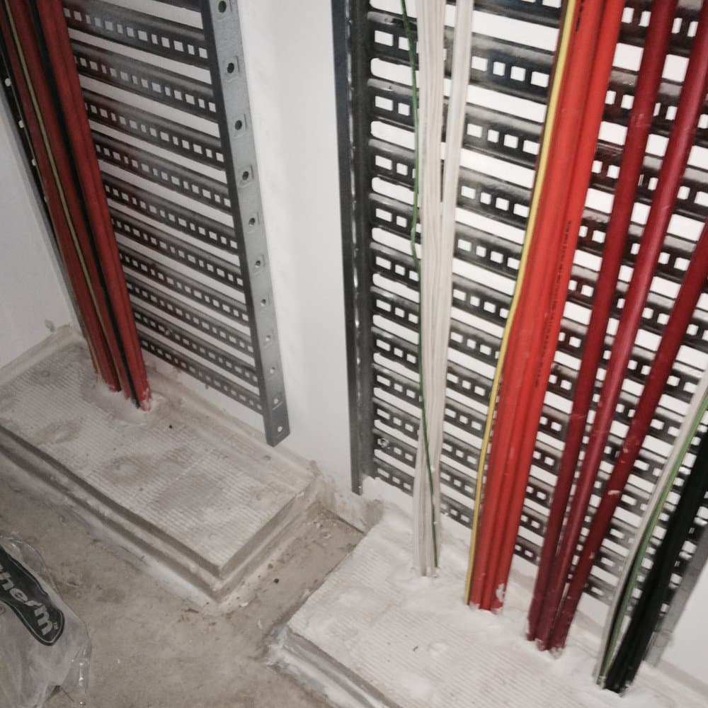 Cables running bare through wall penetrations before rectification.
